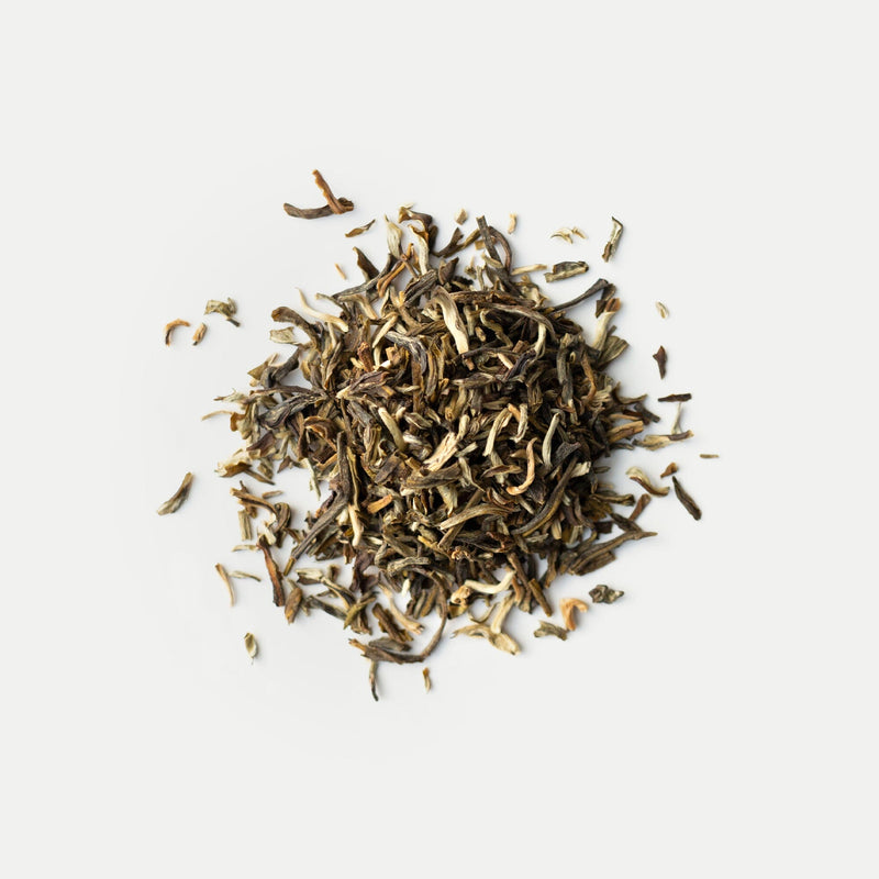 A small pile of loose leaf dried Jasmine Green Tea from Rishi Tea & Botanicals, featuring the delicate aroma of Yin Hao Jasmine from the 2025 harvest, rests on a plain white background.