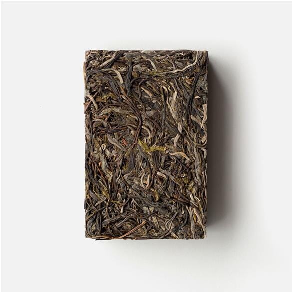 A piece of Laos Sheng Pu’er Tea Brick Vintage 2022 by Rishi Tea & Botanicals on a white background.