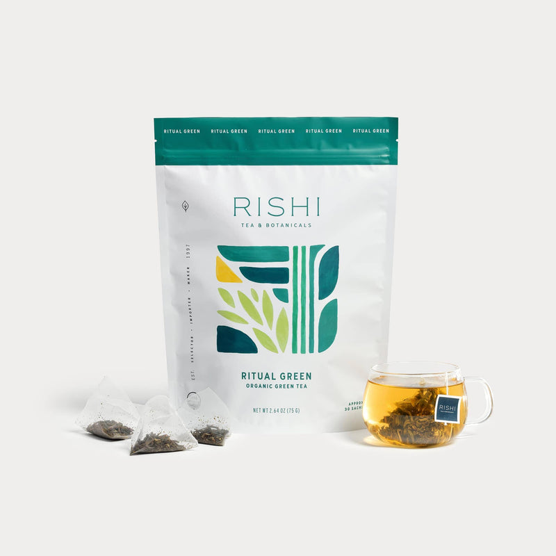 A package of Rishi Tea & Botanicals Ritual Green organic tea with three sachets and a glass cup of brewed tea, showcasing its natural sweetness and subtle floral notes.