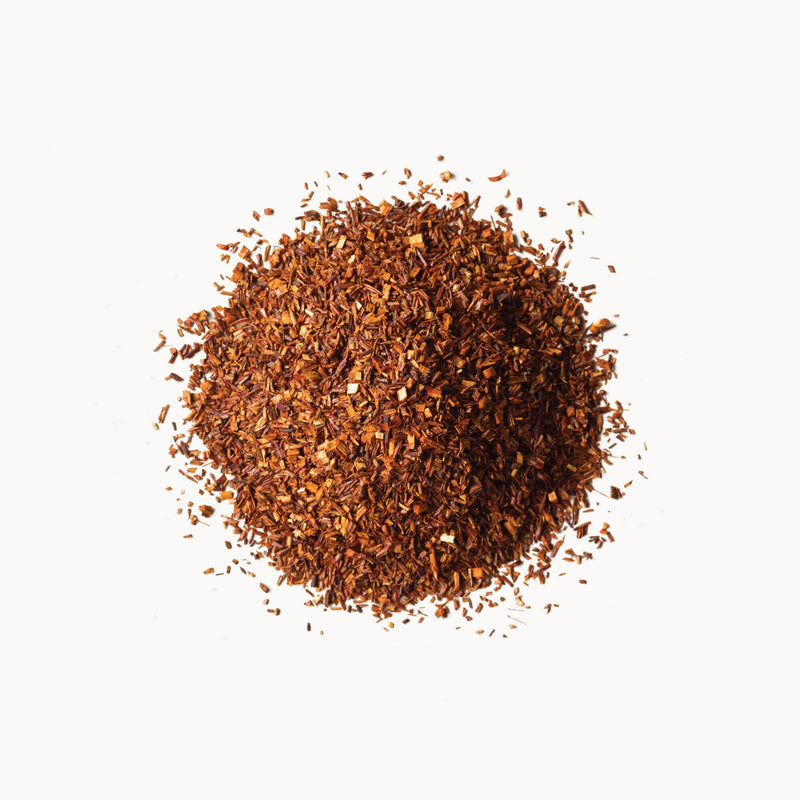 A pile of red Rishi Tea & Botanicals rooibus tea on a white background.