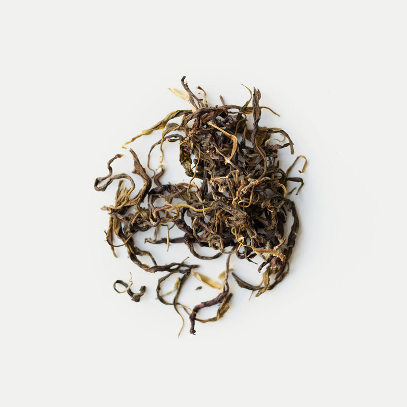 Rishi Tea & Botanicals' sun-dried green tea leaves are loosely arranged in a small pile on a white background.