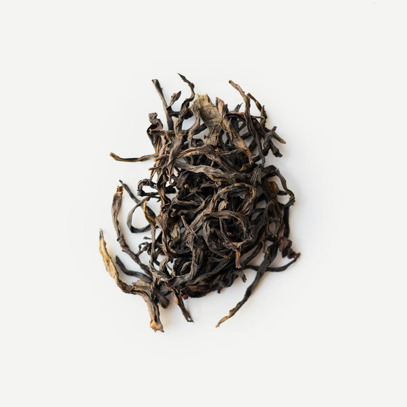 A pile of loose, dried Phoenix Mountain oolong tea leaves from Rishi Tea & Botanicals arranged on a white background.